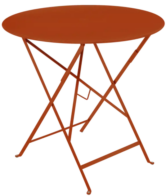 Candied orange Fermob outdoor round bistro table with 77cm diameter, folding metal design for small terrace or patio use.
