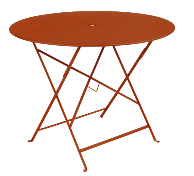 Load image into Gallery viewer, Fermob round bistro table with a deep orange finish, metal construction, outdoor setting, and a central parasol hole.
