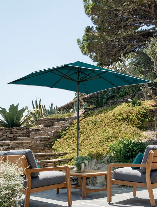 Lodge Fermob outdoor teak armchair with low armrests, designed for hotel terrace seating in a stylish outdoor setting.