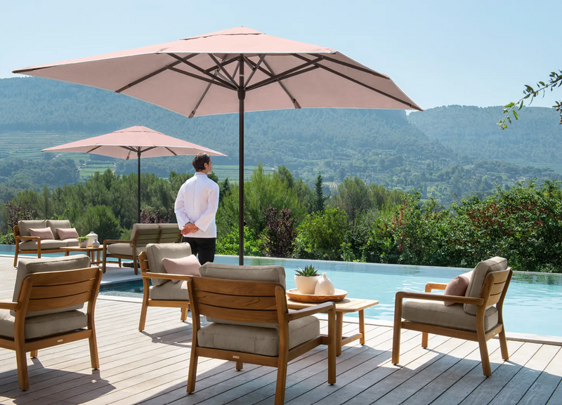 Load image into Gallery viewer, Fermob Lodge Low Armchair outdoor teak seating on hotel terrace, showing sleek design and natural wood finish.
