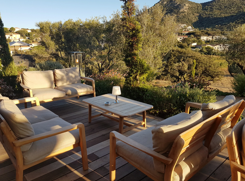 Load image into Gallery viewer, Fermob Lodge low armchair for outdoor teak seating, shown on hotel terrace with stylish, weather-resistant design.
