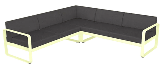 Fermob Bellevie Composition 2 outdoor sofa set with frosted lemon and graphite grey cushions on a patio.
