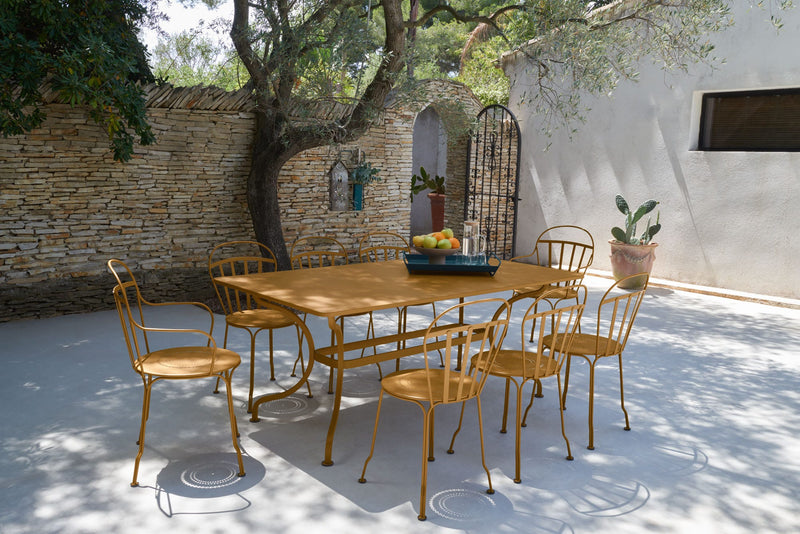 Load image into Gallery viewer, Fermob Louvre chairs in Gingerbread around a table on a sunny courtyard
