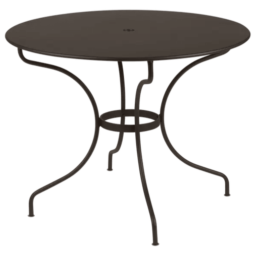 Fermob OPÉRA+ outdoor metal table with 96 cm diameter, suitable for five seating, shown on patio furniture setting.