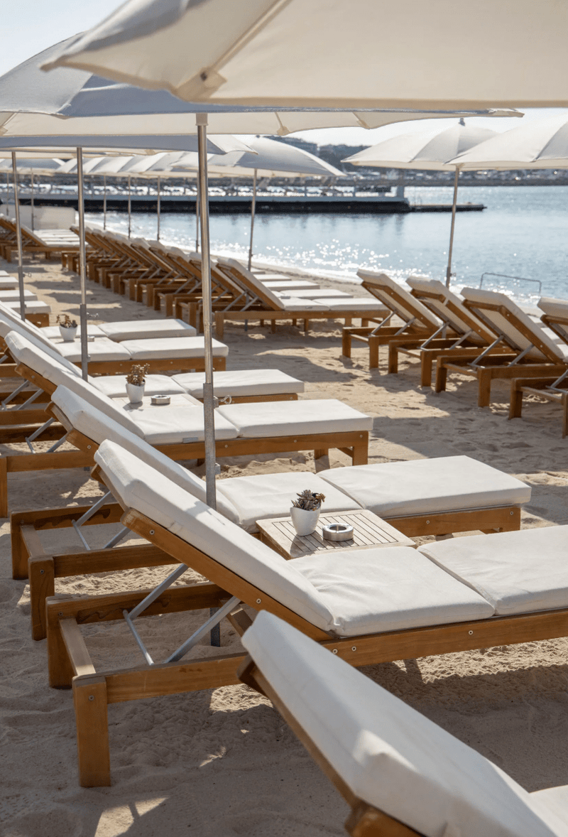 Load image into Gallery viewer, Fermob IBIZA teak sunlounger with wooden frame on a beach setting, outdoor sunbed for relaxing in the sun.
