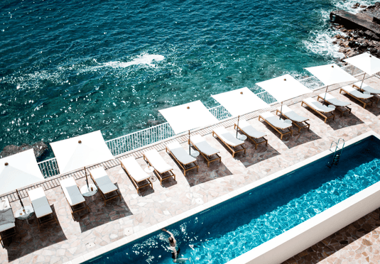Fermob IBIZA teak sunlounger outdoor lounge chair by the poolside, featuring a sleek teak design and comfortable seating.