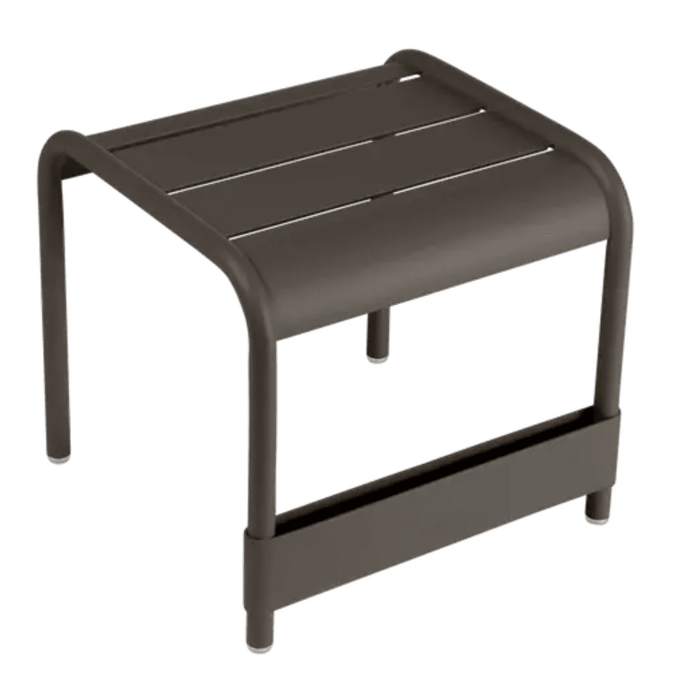 Load image into Gallery viewer, Fermob Luxembourg small low table or footrest, 44x42 cm, with a sleek modern design, shown in a cozy outdoor setting.
