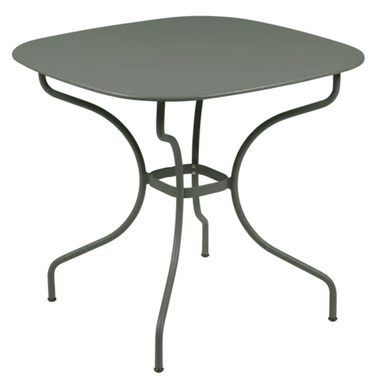 Fermob OPÉRA+ Carronde outdoor metal table, 82x82 cm, shown in a garden setting with a modern design and smooth surface.