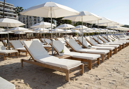 Fermob IBIZA teak outdoor sunlounger with adjustable backrest, placed poolside in an outdoor lounge setting.