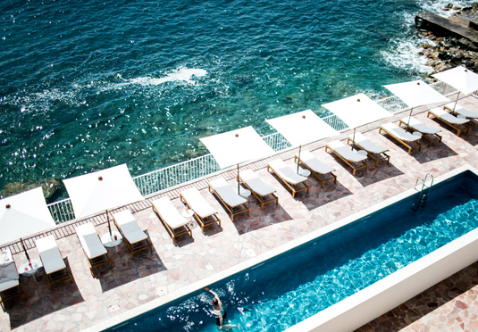 Fermob IBIZA teak sunlounger outdoors by the pool, featuring a sleek design and comfortable seating for relaxing outdoor lounging.