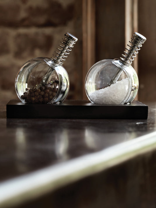 XD Design Planet pepper and salt set with matching ceramic grinders on a wooden countertop, modern kitchen decor.