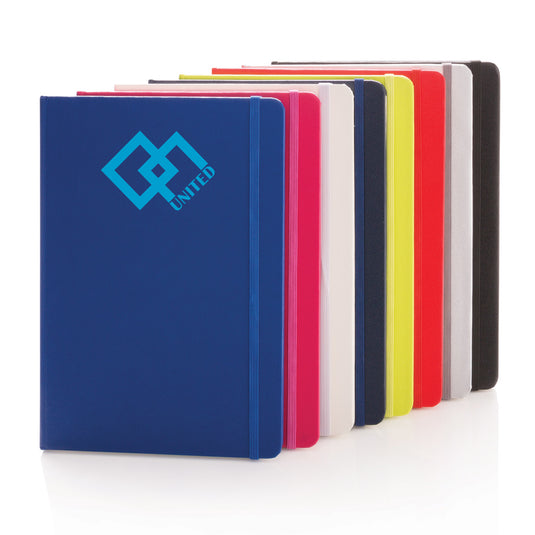 A classic hardcover A5 notebook from XD Collection with a sleek black cover and gold-embossed logo, open to show lined pages.