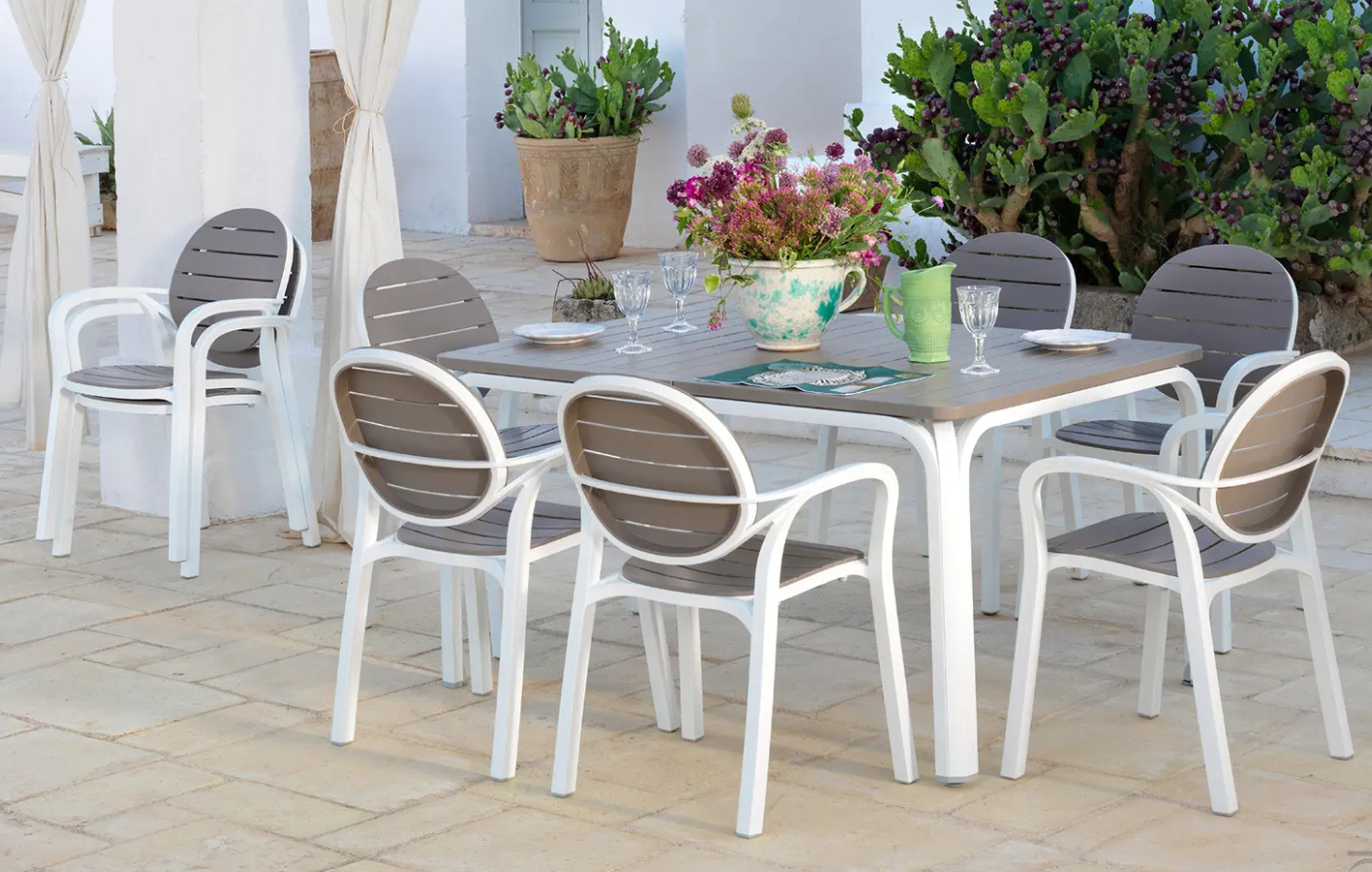 Nardi Palama outdoor armchair with white woven rattan design, featuring a curved armrest and plush cushion for outdoor relaxation.
