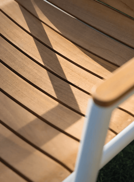 Fermob Pilotis teak armchair with curved armrests and slatted design, ideal for outdoor restaurant seating.