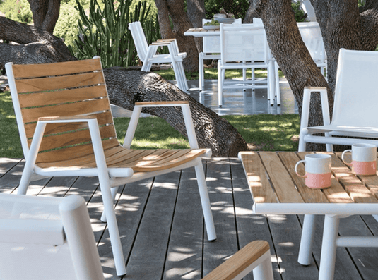 Red ochre Fermob Pilotis teak outdoor armchair with low arms, showcasing solid teak construction and modern design.