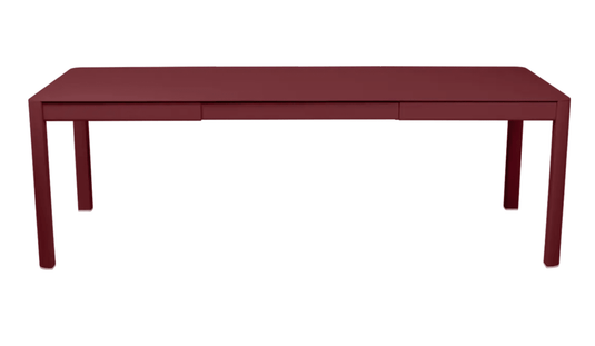 Chilli red Fermob Ribambelle extendable metal table outdoors, large 10-seater, perfect for outdoor hospitality and gatherings.