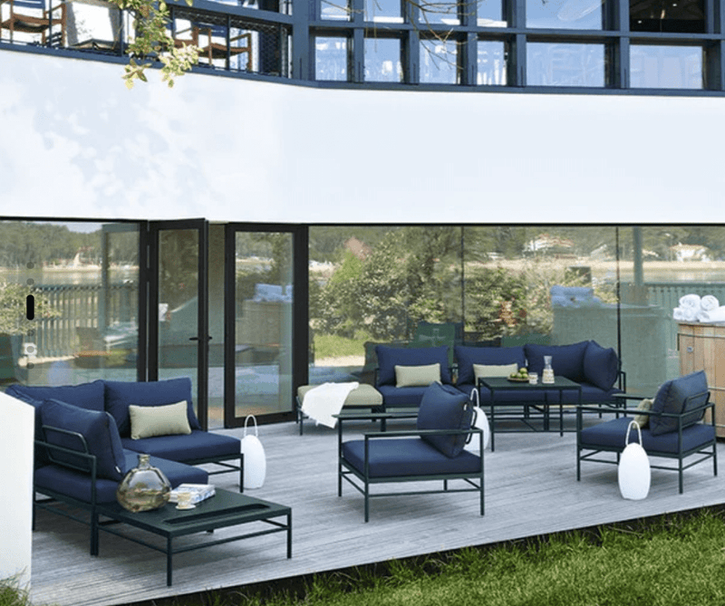 Load image into Gallery viewer, Rivage Ottoman - Custom Wood DesignsFermob Rivage Ottoman outdoor furniture with metal frame, shown with protective cover on a patio setting.Ottoman Outdoor Furniture Fermob Metal24575201360023Rosemary Twine
