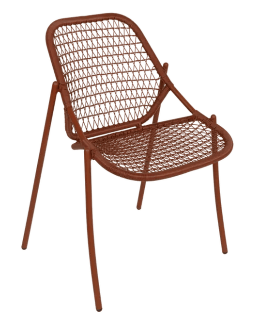 Red Ochre Fermob Sixties Stackable Chair made of knitted outdoor furniture, shown stacked and ready for outdoor use.